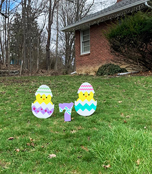Lawn decoration of two striped eggs, with chicks just hatching, on either side of the number 7.