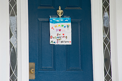 Blue door with a hand-made sign: Thank you for delivering our mail! Hero.