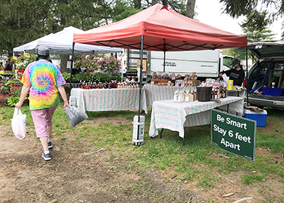 farmers market with masked shoppers and 6 feet apart signs