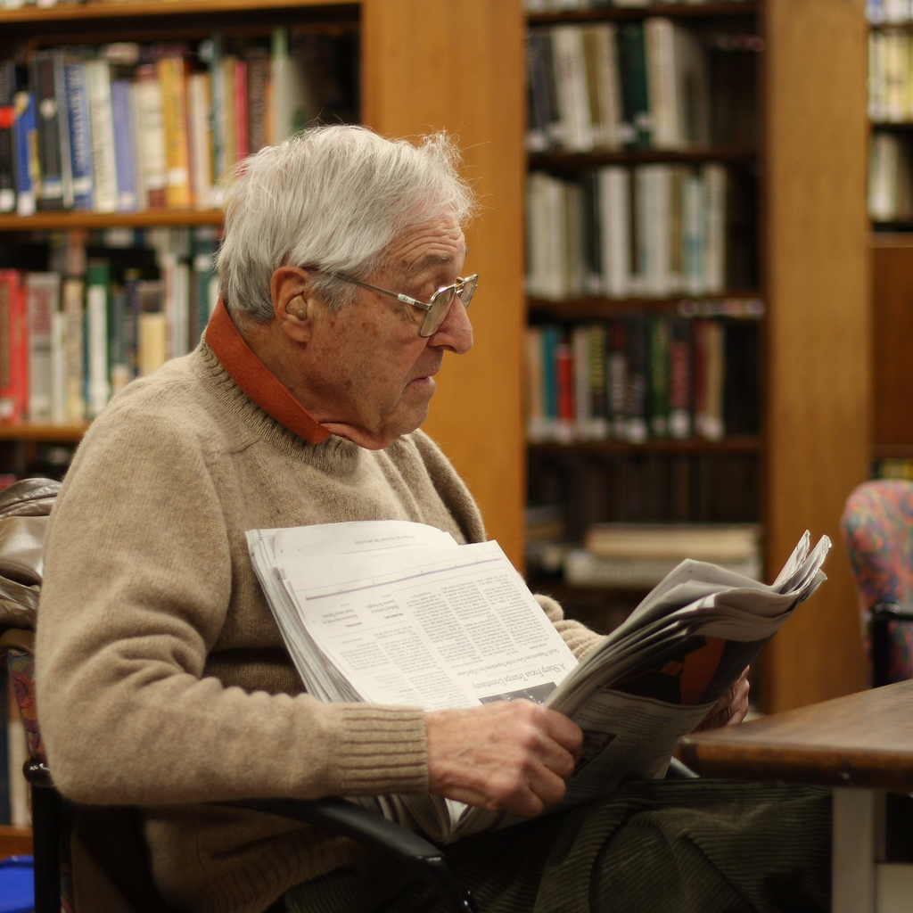 man reading newspaper in library