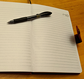 journal, open to a blank page, with a pen atop it