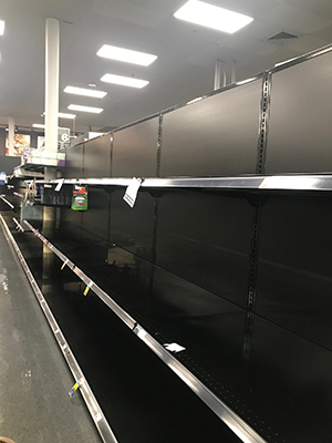 The aisle of a grocery store, with empty shelves.